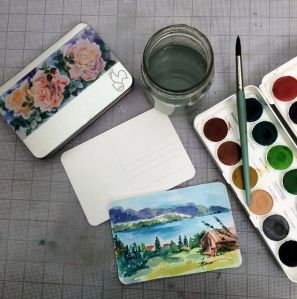 The tin of papers, watercolors, brush, etc.